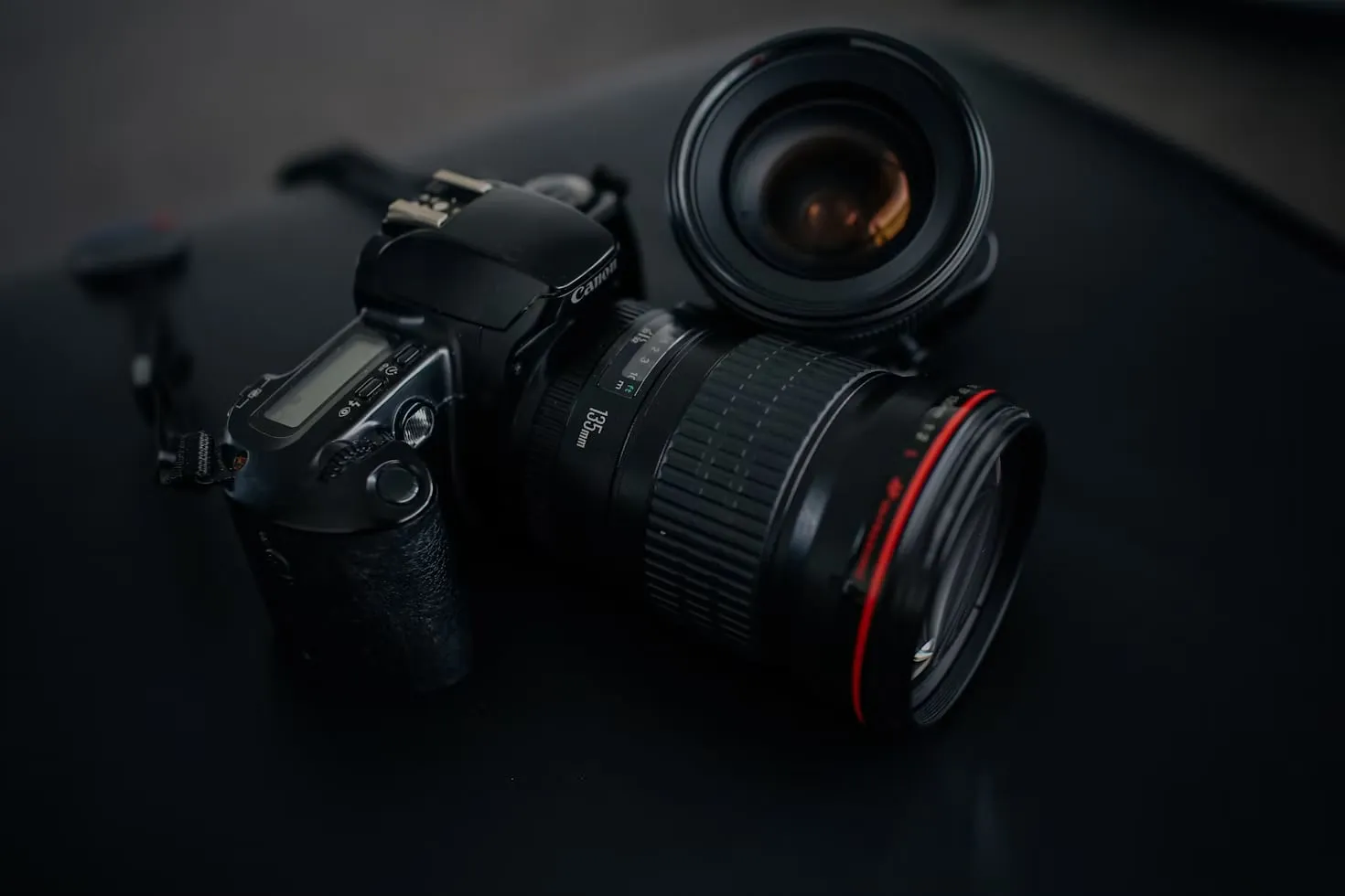 A DSLR camera with an attached lens and a second lens beside it.