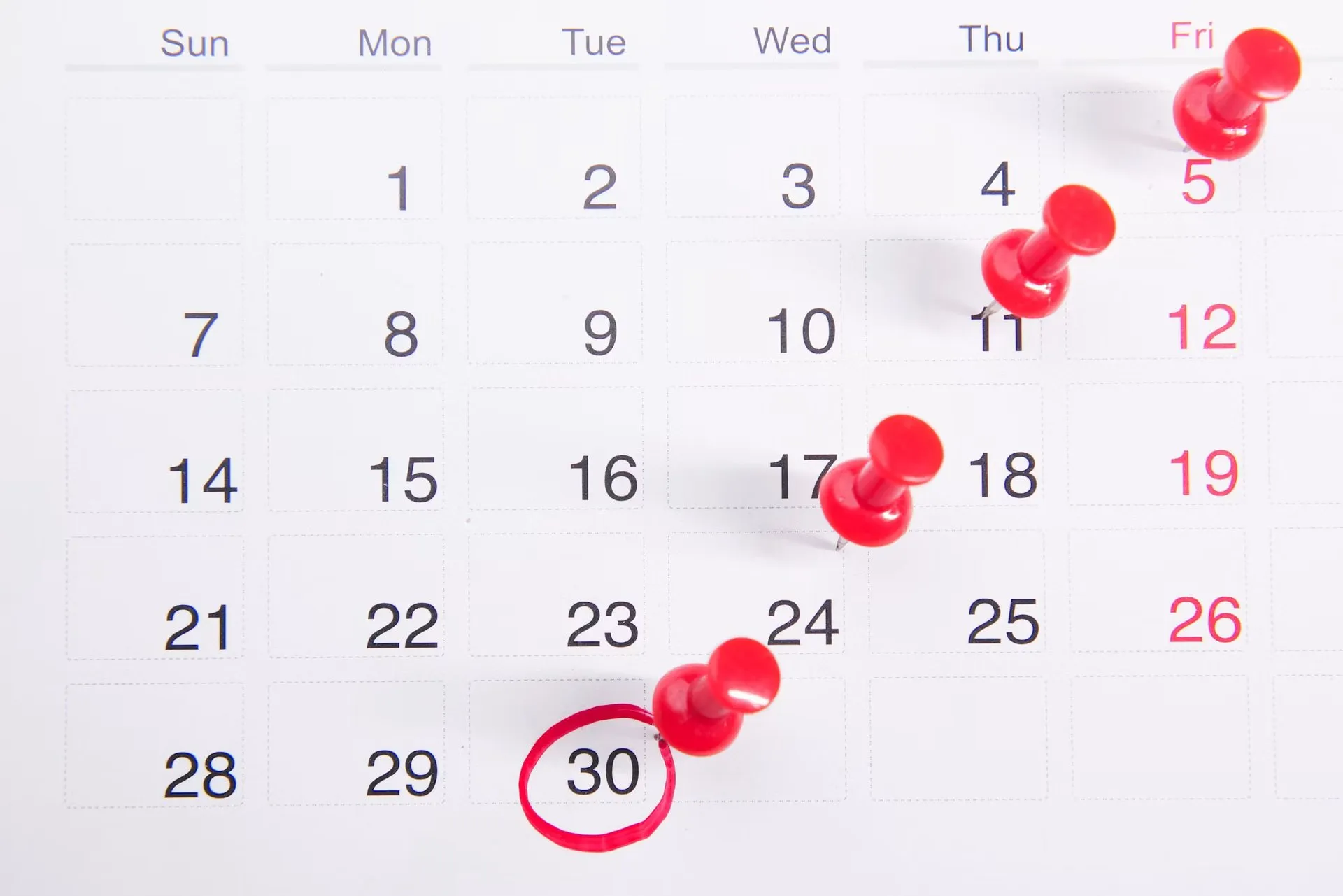 Red pushpins and a circled date mark several points on a paper calendar.
