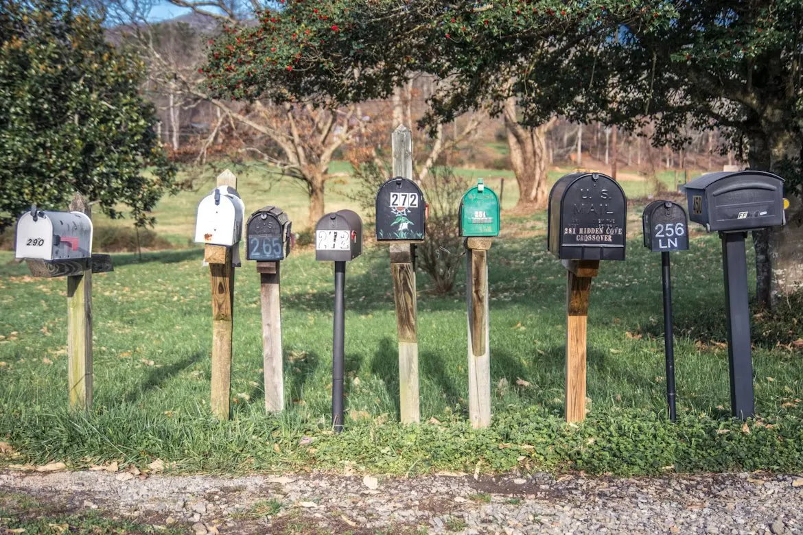 Several individually numbered mailboxes stand together beside a grassy roadside.