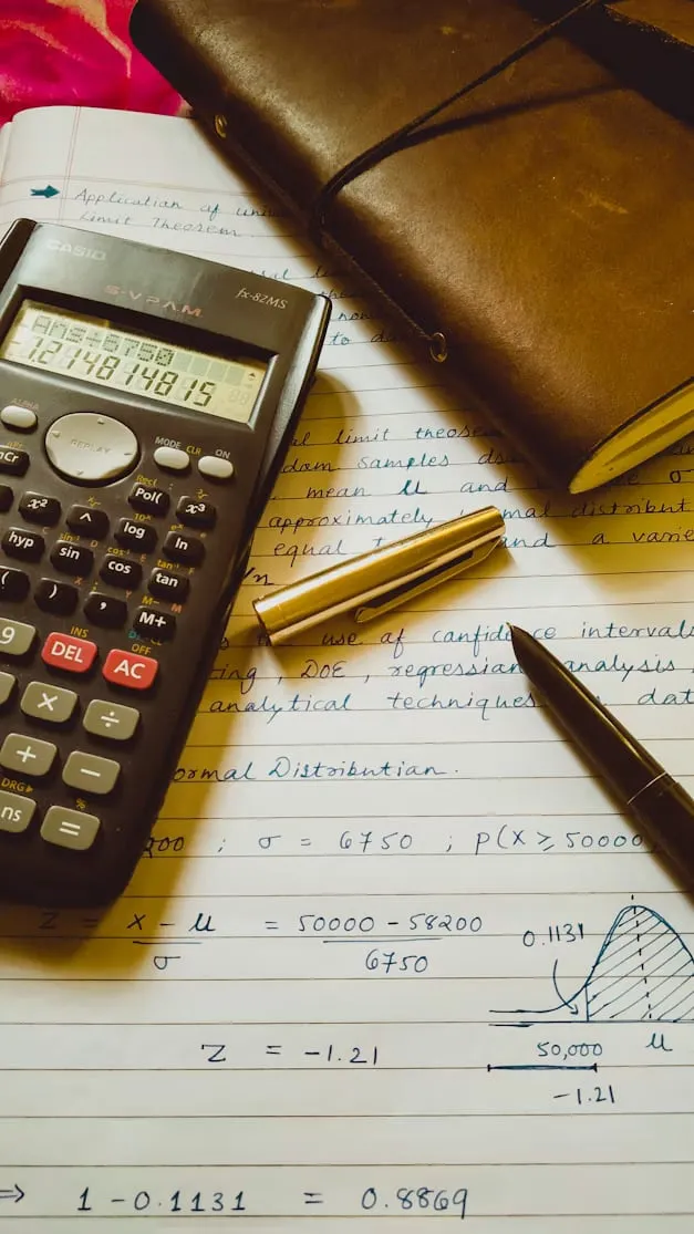 A scientific calculator and pen on handwritten statistics and regression notes.