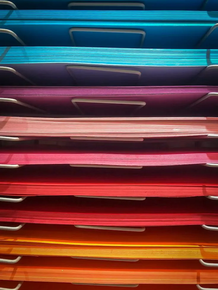 Blue, purple, pink and orange hanging document folders are arranged in rows.